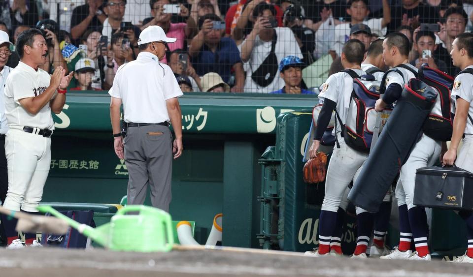 引き揚げる横浜ナイン（右）を拍手で見送る日南学園・金川監督（左）＝撮影・中田匡峻