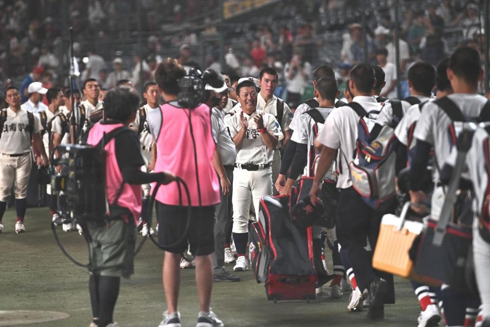 試合後、引き揚げる横浜ナインに拍手をする日南学園・金川豪一郎監督（後方中央）＝撮影・開出牧