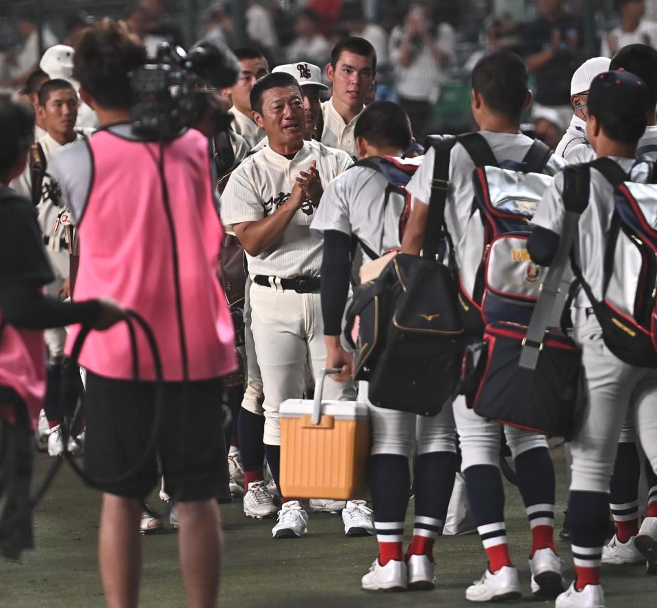 試合後、引き揚げる横浜ナインに拍手をする日南学園・金川豪一郎監督（中央）＝撮影・開出牧