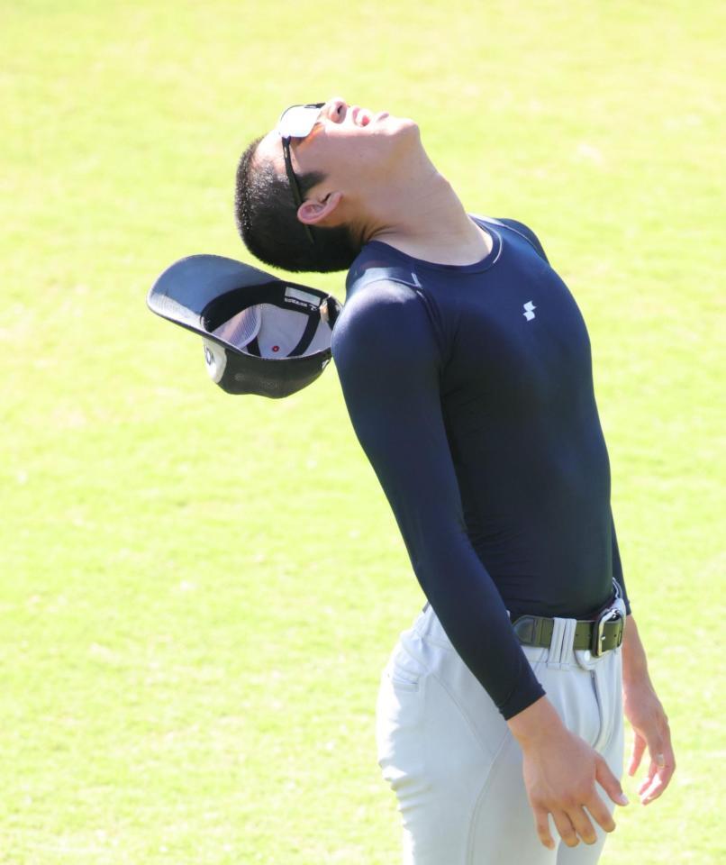 ストレッチで首をそらす横浜・織田翔希は帽子が脱げ苦笑い（撮影・坂部計介）