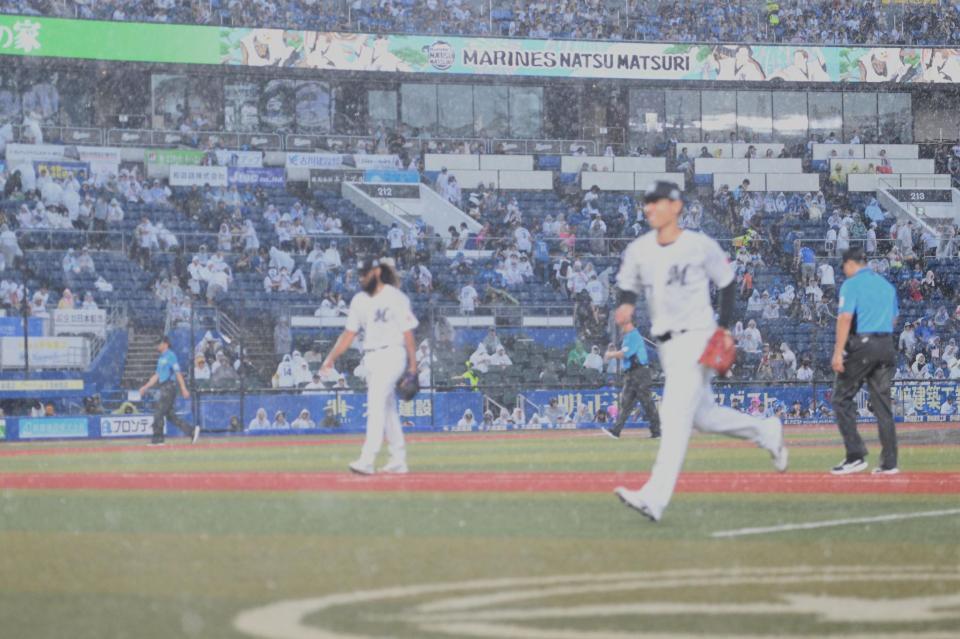 １回、天候不良により一時中断となりベンチへ引き揚げるジャクソン（後方）らロッテナイン（撮影・開出牧）