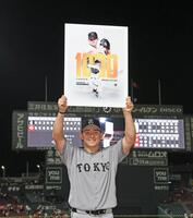 お立ち台で記念のボードを手に笑顔を見せる小笠原（撮影・北村雅宏）