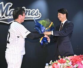 　引退会見後に益田（左）から花束を受け取る唐川（撮影・開出牧）