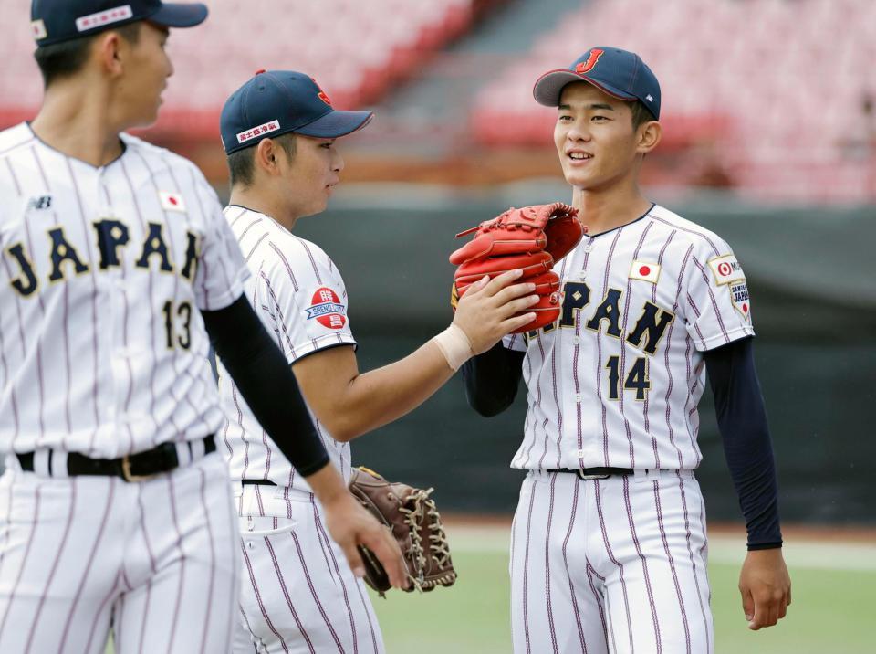４回途中から登板して空振り三振を奪い、笑顔でタッチを交わす前田（右）＝台北（共同）