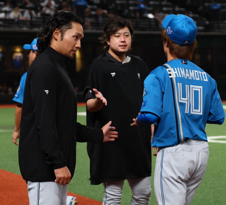 １２回引き分け試合となり、中継ぎ陣を迎える伊藤（左）＝撮影・中島達哉
