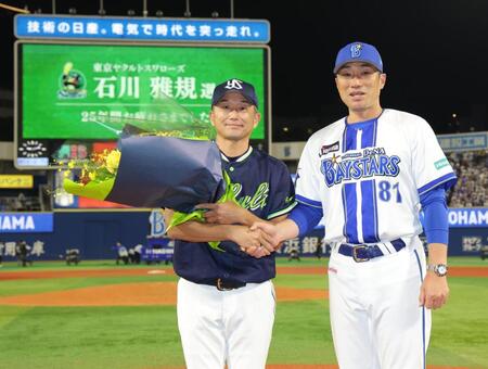相川監督（右）から花束を受け取り、握手する石川（撮影・西岡正）