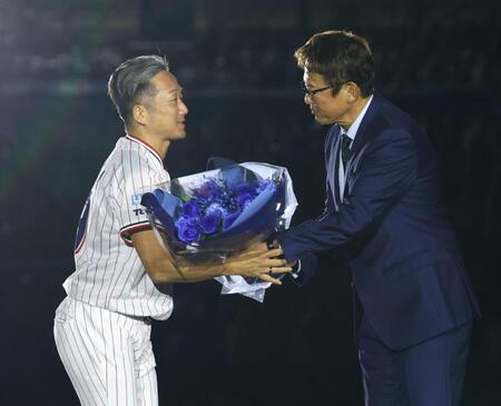 古田敦也氏（右）から花束を受け取るヤクルト・石川雅規＝明治神宮球場（撮影・中島達哉）