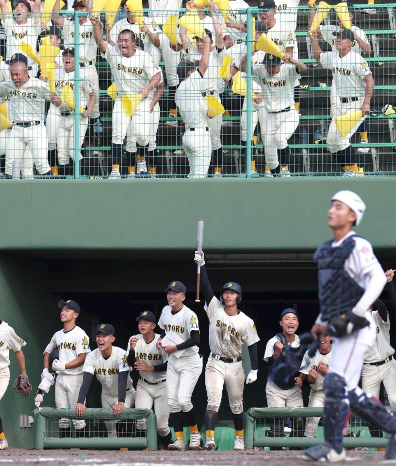 ７回、崇徳・河野拓真が適時打を放ち、喜ぶ崇徳ナインと崇徳応援団（手前右下は広陵主将・勝本晴太）＝撮影・北村雅宏
