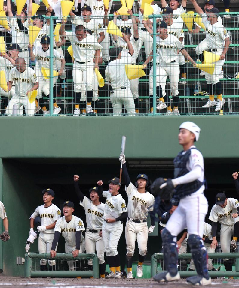 ７回、崇徳・河野拓真が適時打を放ち、喜ぶ崇徳ナインと崇徳応援団（手前右下は広陵主将・勝本晴太）＝撮影・北村雅宏