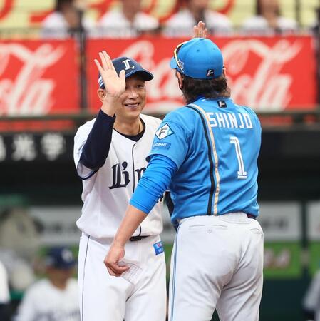 メンバー表を交換し、新庄監督（右）とハイタッチを交わす西口監督（撮影・中島達哉）
