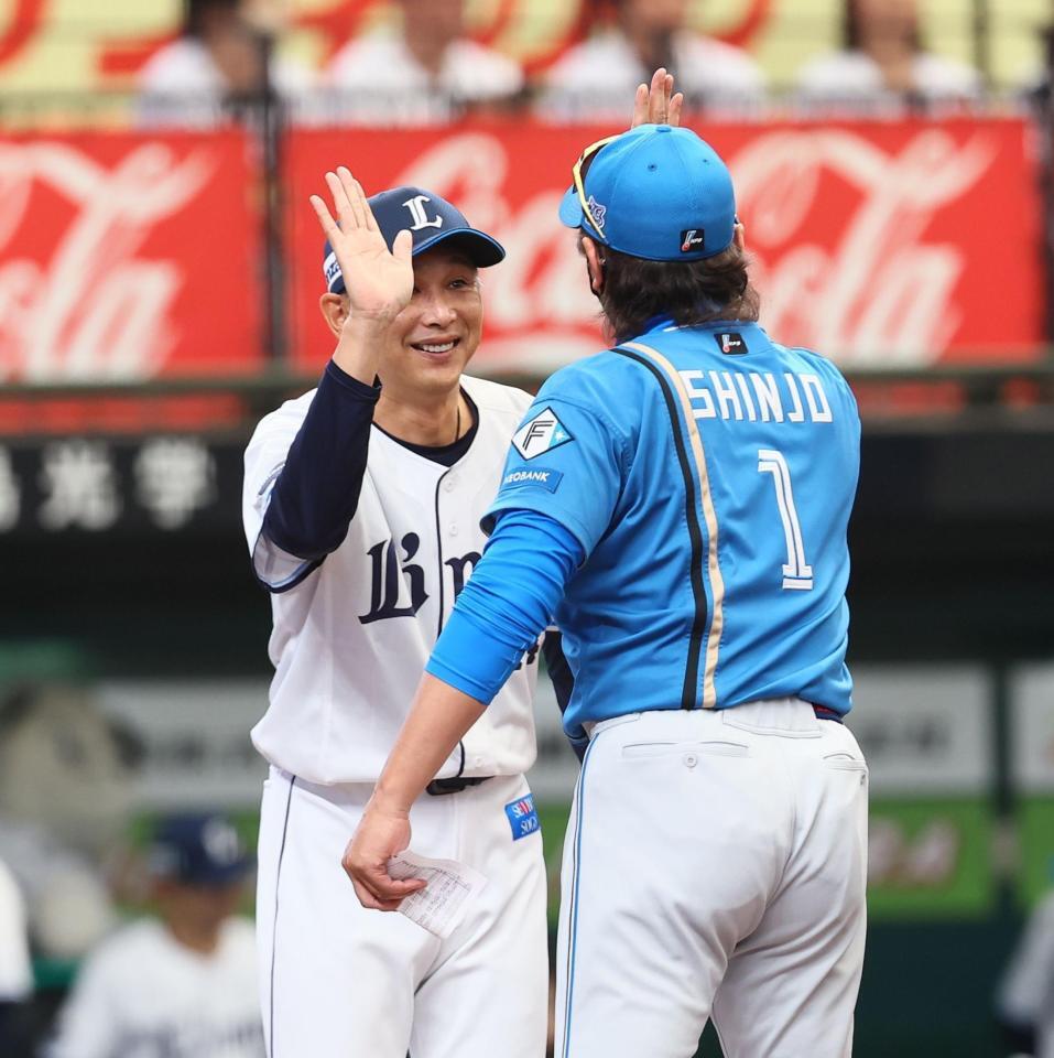 メンバー表を交換し、新庄監督（右）とハイタッチを交わす西口監督（撮影・中島達哉）