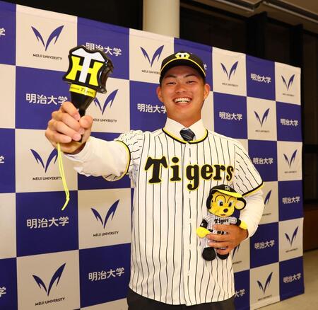 阪神からドラフト１位指名を受け、笑顔で記念撮影に応じる明大・榊原七斗（撮影・中島達哉）