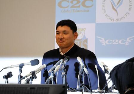 照れ笑いを浮かべて会場入りする山梨学院・菰田