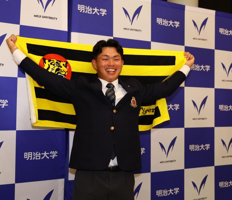 阪神からドラフト１位指名を受け、笑顔で記念撮影に応じる明大・榊原七斗（撮影・中島達哉）
