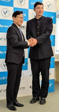 ドラフト１位指名した山梨学院・菰田（右）と笑顔で握手する日本ハム・栗山英樹ＣＢＯ