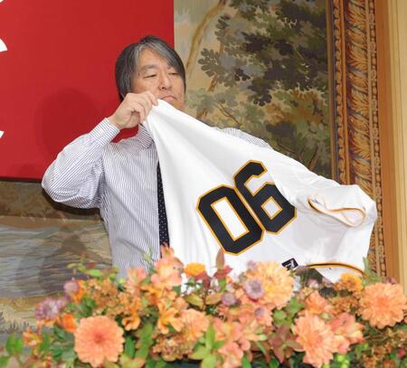 　ユニホームに袖を通す巨人・松井新監督（撮影・西岡正）