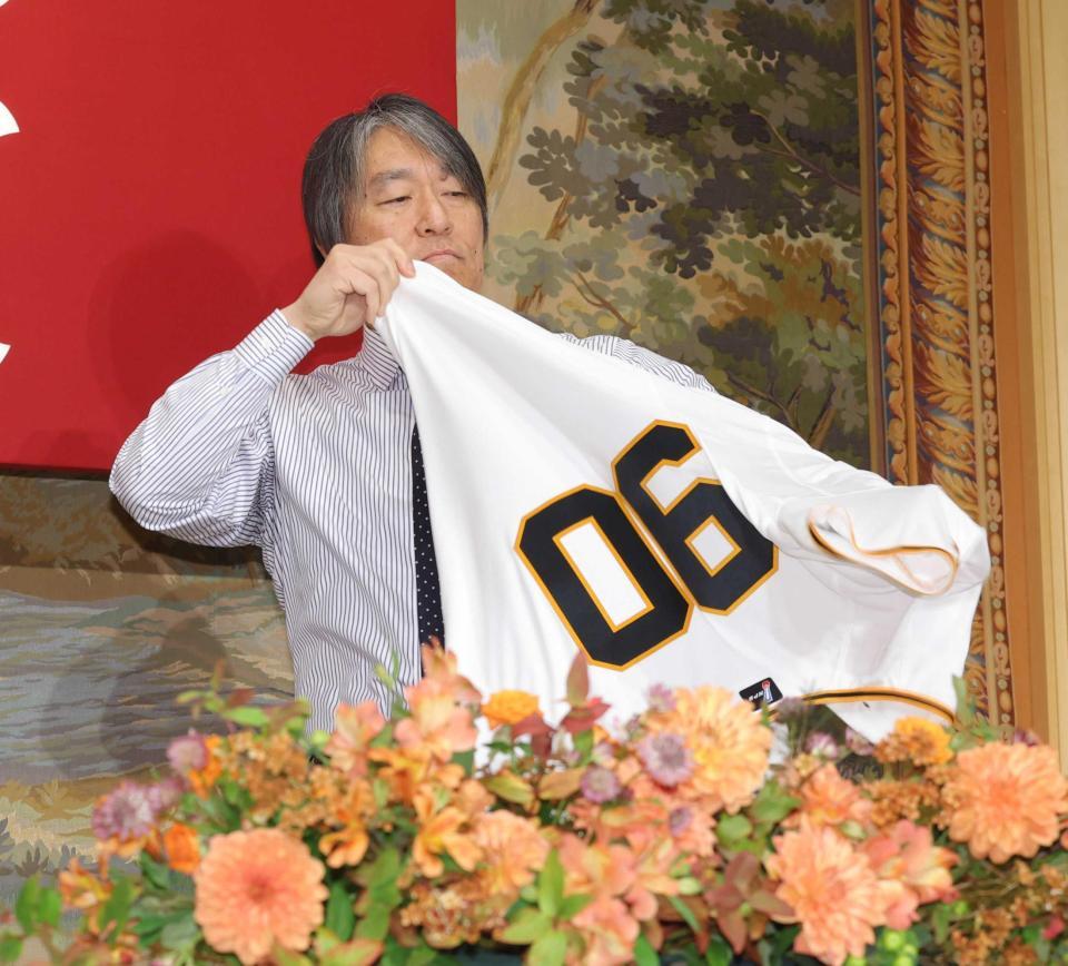 　ユニホームに袖を通す巨人・松井新監督（撮影・西岡正）
