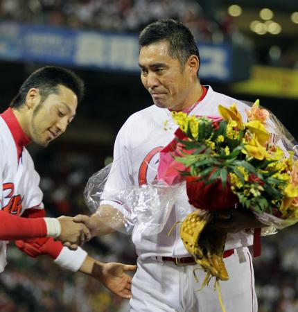 　引退登板を終えた菊地原は花束を手に涙を浮かべ握手を交わす（撮影・出月俊成）
