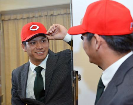 　似合ってます？カープの真っ赤な帽子をかぶり、鏡に映る自身の姿を見つめるＪＲ東日本・田中（撮影・村中拓久）