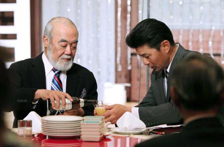 　安仁屋ＯＢ会長（左）からビールをつがれ、恐縮する緒方監督（撮影・出月俊成）