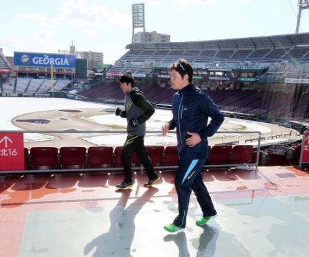 まだ雪が残るマツダスタジアムのコンコースをランニングする広島・新井貴浩（右）＝マツダスタジアム（撮影・出月俊成）