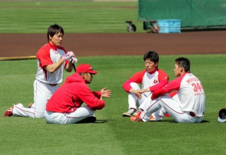 練習前に芝生に座りこみ（右から）鈴木誠、野間、丸に語りかける緒方監督（左から２人目）＝撮影・出月俊成