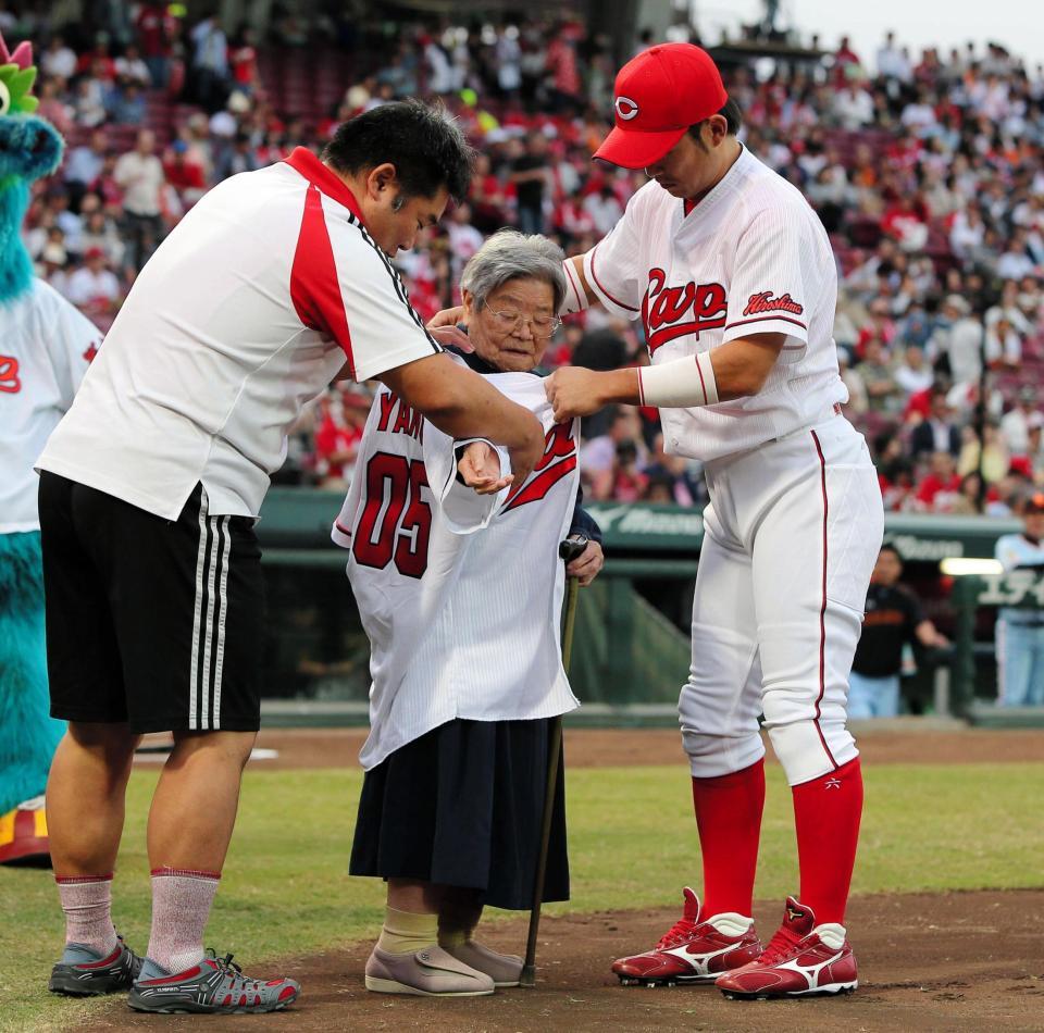 広島・梵から特製のユニホームを着せてもらう山田アヤノさん（中央）＝マツダスタジアム（撮影・出月俊成）