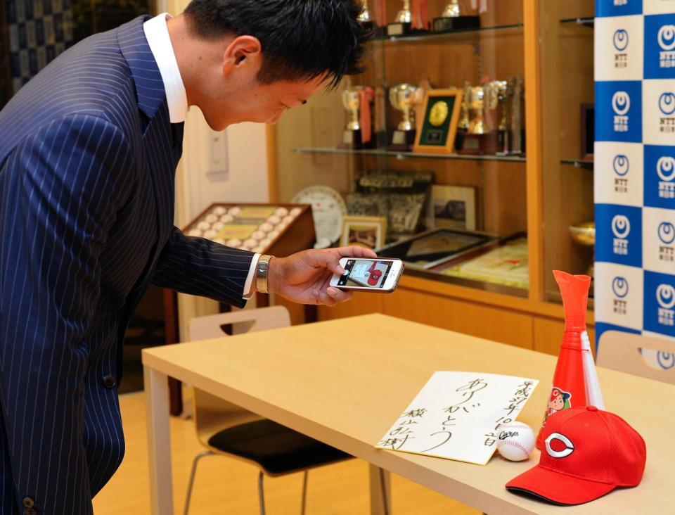 携帯電話でカープグッズの写真を撮る横山（撮影・佐々木彰尚）