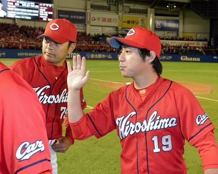 今季６勝目を挙げ広島・緒方監督（左）とタッチをかわす広島・野村＝ＱＶＣマリンフィールド（撮影・堀内翔）