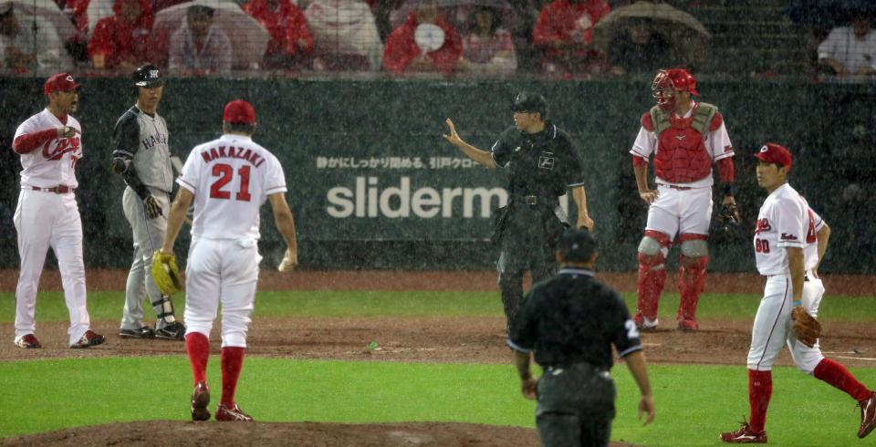 ９回阪神無死一塁、打者・阪神・高山俊のとき、激しく降る雨に広島・緒方孝市監督（左）が試合を止めに入る＝マツダスタジアム（撮影・田中太一）