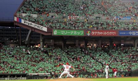 　平和を願う緑色の紙をファンが掲げる中、力投する黒田（撮影・吉澤敬太）