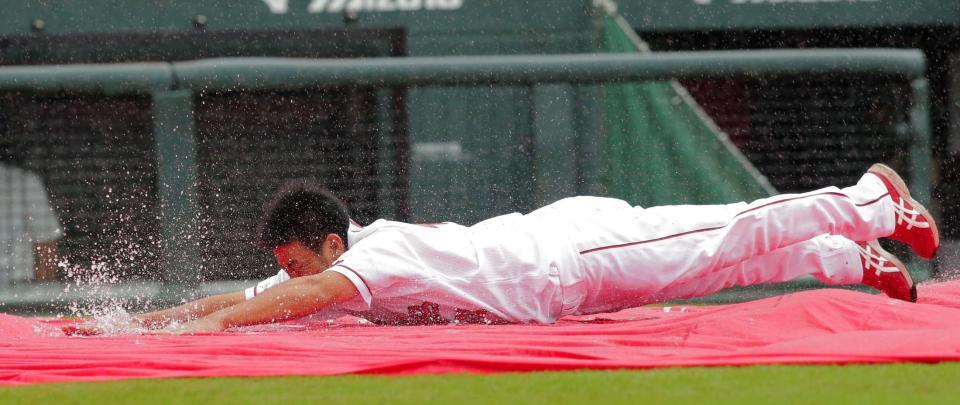 雨天中止となり、水たまりにヘッドスライディングし、ファンの声援に応える広島・倉義和＝マツダスタジアム（撮影・吉澤敬太）