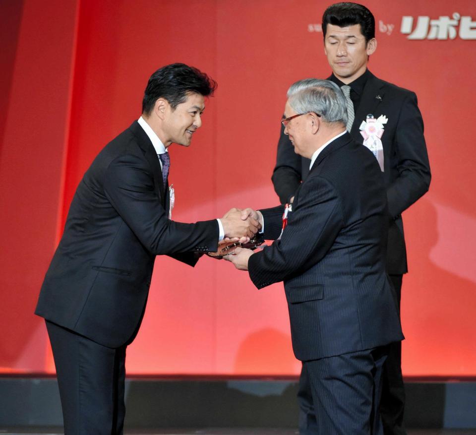 　最優秀監督賞を受賞し、熊崎コミッショナー（右）と握手を交わす緒方監督