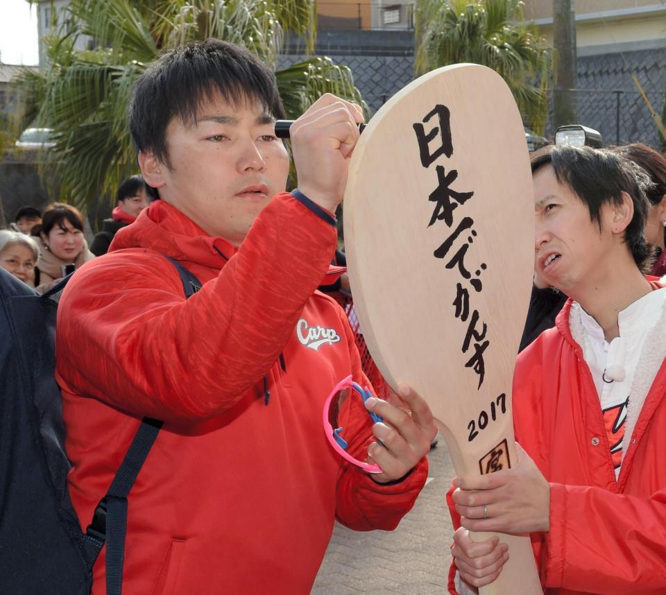 アンガールズが持参した大しゃもじにサインする広島・丸佳浩＝宮崎・日南（撮影・吉澤敬太）