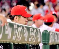 ベンチの柵にもたれかかり試合を見つめる岡田