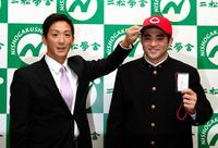 広島・尾形佳紀スカウトから帽子かぶらせてもらう二松学舎大付高・永井敦士（右）左手には緒方孝市監督からドラフトパスに書かれたサインも＝二松学舎大付高（撮影・三好信也）