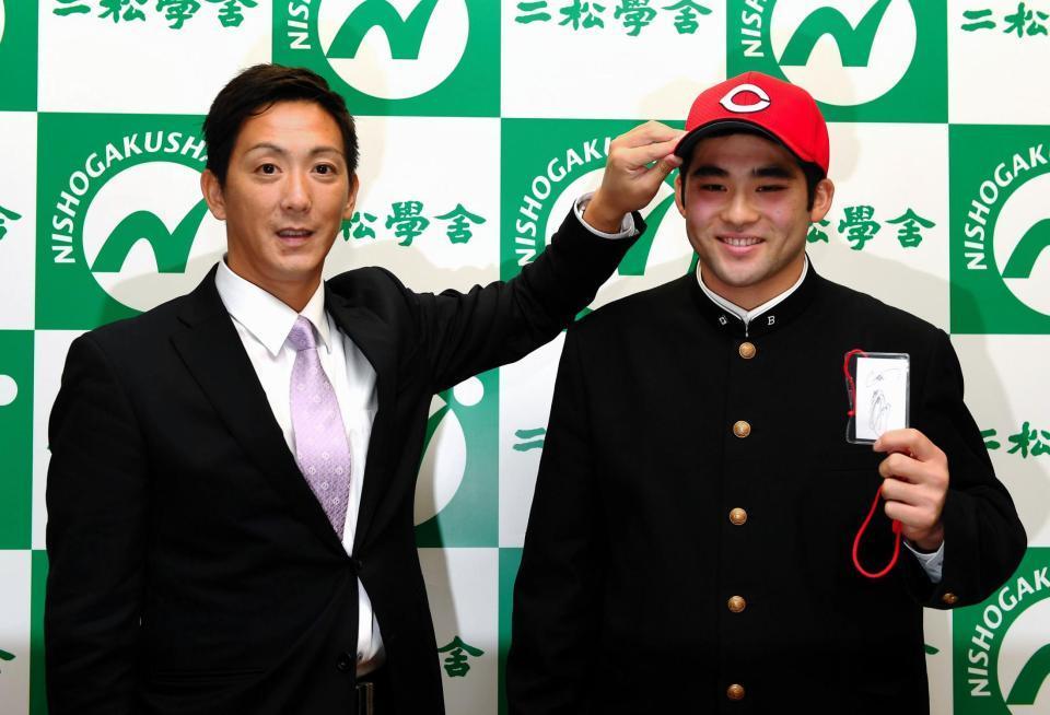 広島・尾形佳紀スカウトから帽子かぶらせてもらう二松学舎大付高・永井敦士（右）左手には緒方孝市監督からドラフトパスに書かれたサインも＝二松学舎大付高（撮影・三好信也）