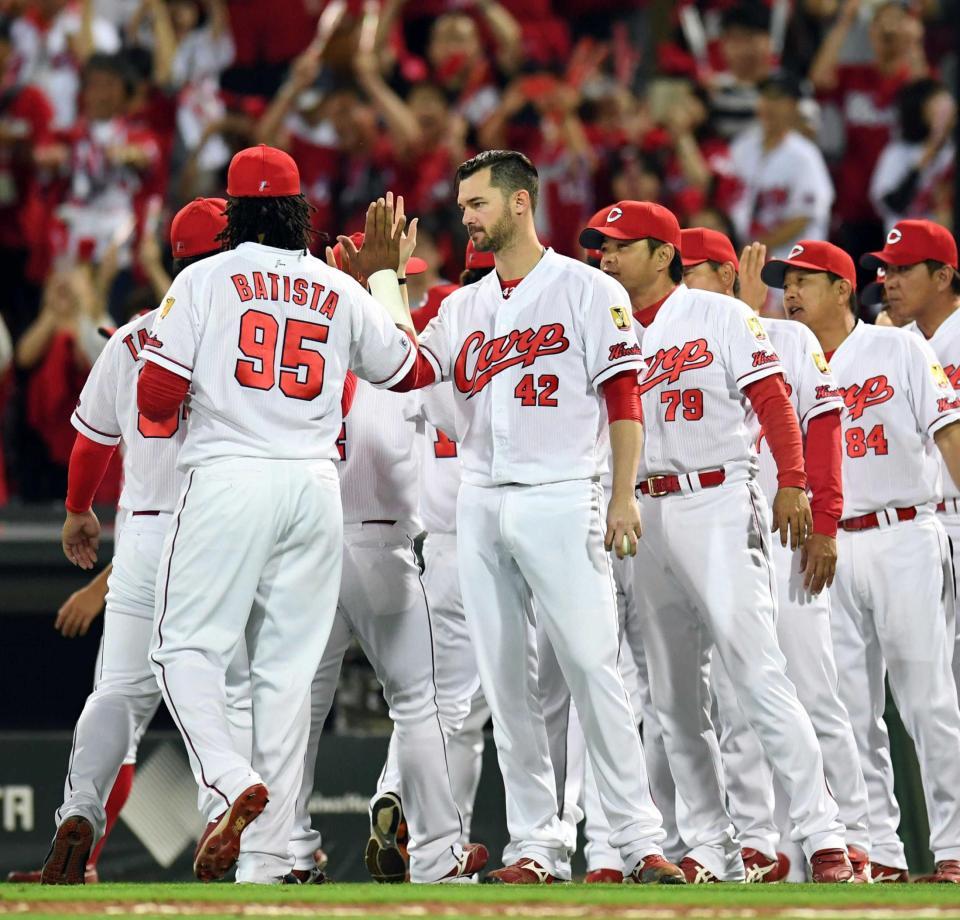 　ハイタッチでナインを迎えるジョンソン（撮影・飯室逸平）
