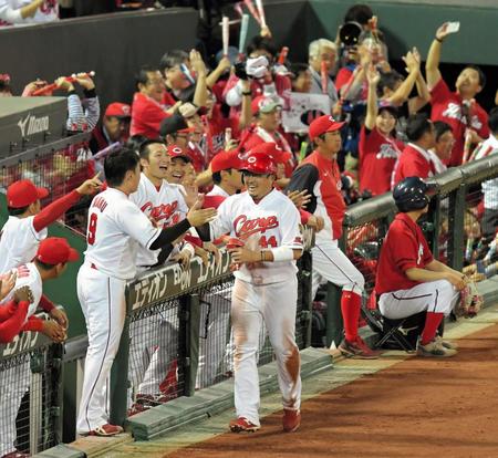 １回、会沢の適時打で生還し、ナインとタッチを交わす松山（中央）＝撮影・高部洋祐