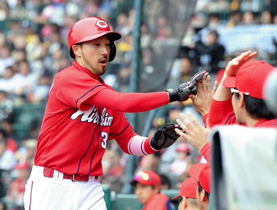 ３回、広島・バティスタのタイムリーで生還しナインとタッチを交わす広島・菊池涼介＝甲子園（撮影・飯室逸平）