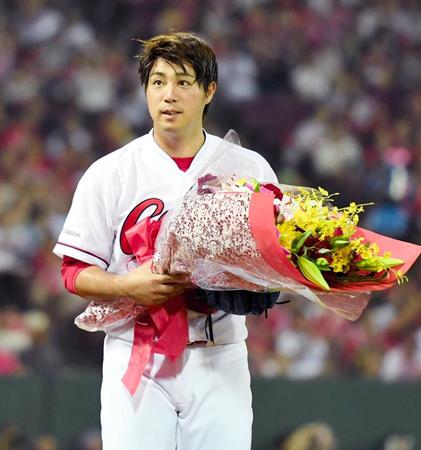 １０００投球回達成し、花束を手にする野村（撮影・飯室逸平）