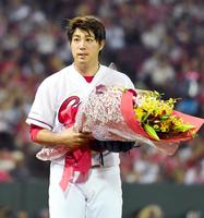 １０００投球回達成し、花束を手にする野村（撮影・飯室逸平）