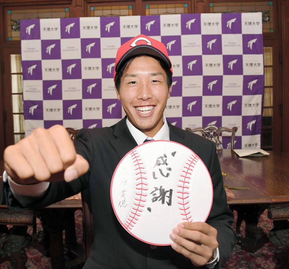 「感謝」と記した色紙を手に笑顔を見せる広島ドラフト５巡目・石原貴規＝奈良・天理大学（撮影・飯室逸平）