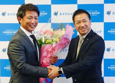 引退記者会見で、エイジェック幹部（右）から花束を受け取る元広島の梵氏