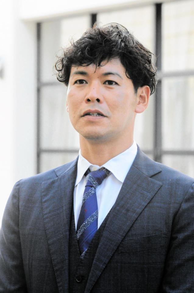 スーツ姿で取材に応じる小窪