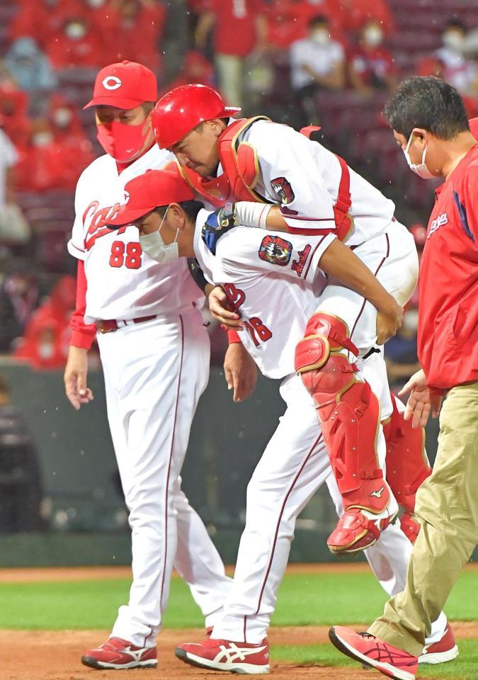 　８回、栗山の三ゴロからの挟殺プレーで脚を負傷し、背負われて引き揚げる会沢。左は佐々岡監督（１５日）