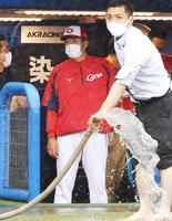 　排水作業が行われている球場を見つめる佐々岡監督