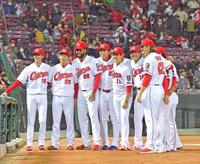 本拠地最終戦で１３勝目を飾り、投手陣と並んで記念撮影する九里（１１）＝撮影・立川洋一郎