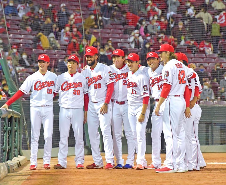 本拠地最終戦で１３勝目を飾り、投手陣と並んで記念撮影する九里（１１）＝撮影・立川洋一郎