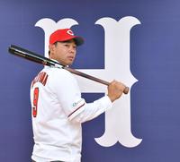 　カープのユニホームに袖を通し気合を見せる秋山（撮影・立川洋一郎）